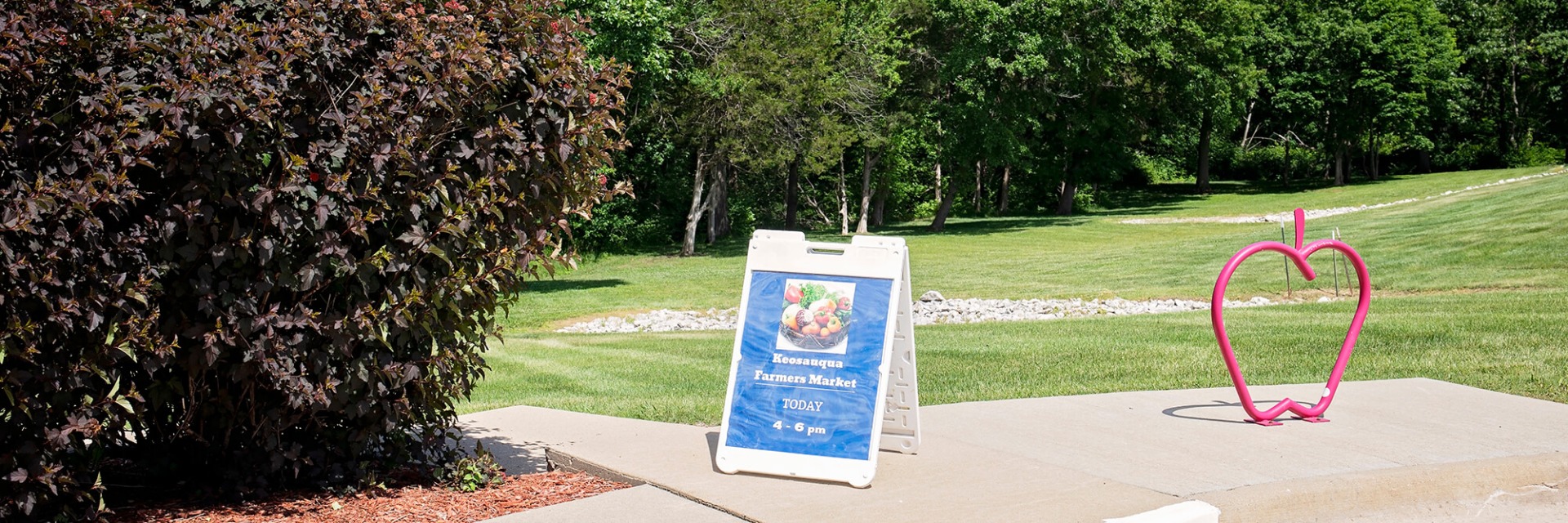 Keosauqua Farmers Market sign next to apple art.